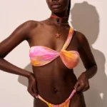 COSTUME DONNA MATINEE DELLA COLLEZIONE ESTATE 2025. FASCIA MONOSPALLA E BRASILIANA A TENDINA NEI COLORI DELL'ARANCIO E DEL ROSA