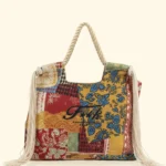 BORSA MARE EFFEK IN TELA DELLA STAGIONE ESTATE 2026. MANICI IN CORDA CON FRANGE LATERALI. BASE PANNA CON FANTASIA TURCHESE, SENAPE E COCCIO