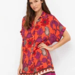 CAMICIONE GISELA DELLA COLLEZIONE ESTATE 2026. 100% VISCOSA A FANTASIA BASE CORALLO CON FIORI VIOLA