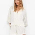 PIGIAMA DO NNA GISELA DELLA COLLEZIONE ESTATE 2026. TSHIRT APERTA E SHORT NEL COLORE PANNA CON LEGGERA FANTASIA SATINATA TONO SU TONO